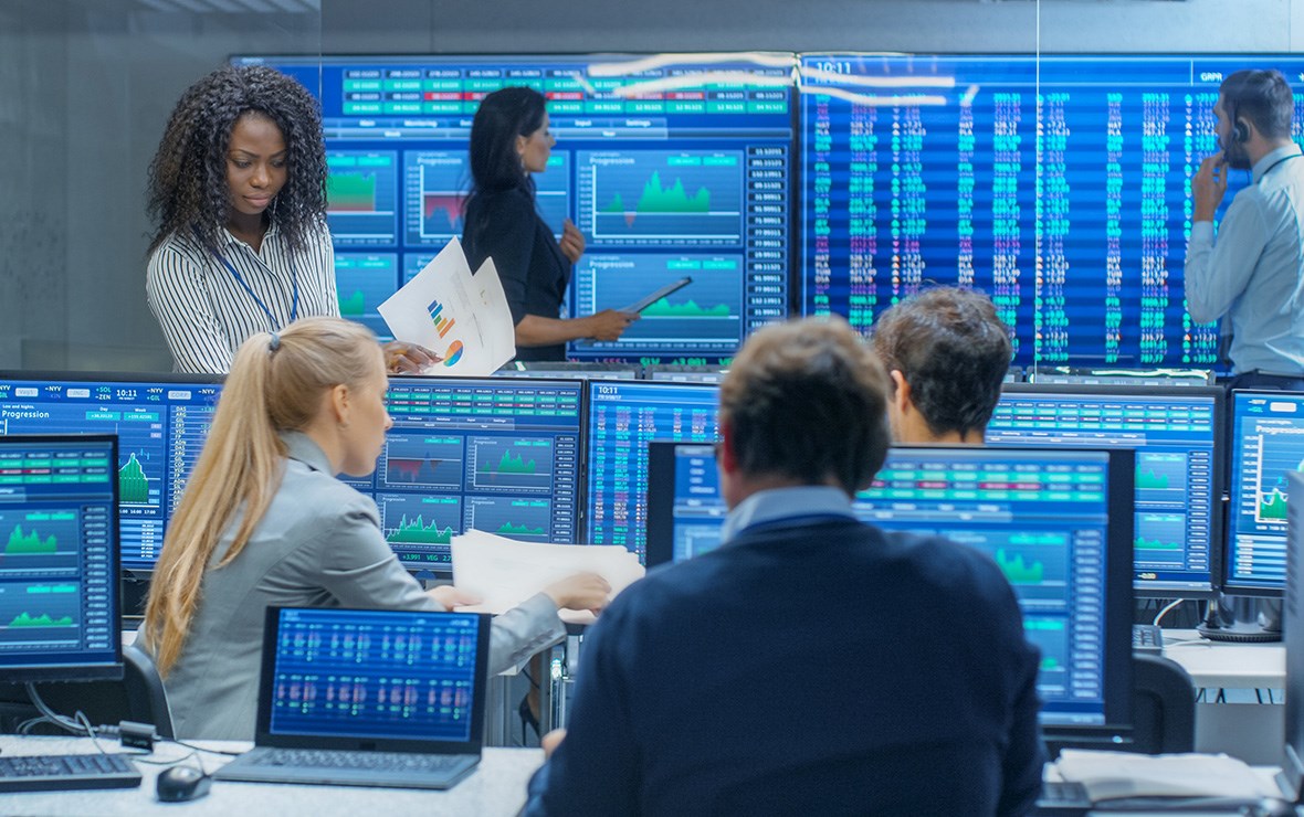 People working in a financial office with lots of screens.